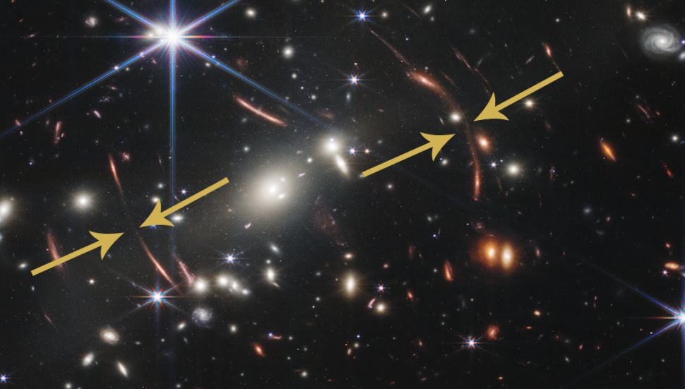 Длинные червеобразные дуги оранжевого света закручиваются по краям скопления галактик. 